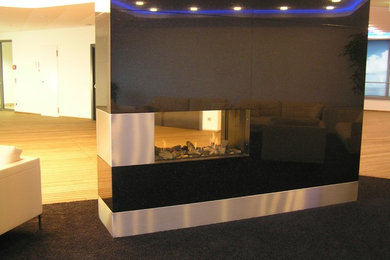 ハンブルクにあるコンテンポラリースタイルのおしゃれなリビング (両方向型暖炉、石材の暖炉まわり) の写真