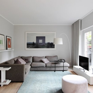 Kleines, Abgetrenntes Modernes Wohnzimmer ohne Kamin mit grauer Wandfarbe, braunem Holzboden, freistehendem TV und braunem Boden in Düsseldorf