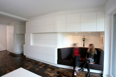 Mittelgroßes, Offenes Modernes Wohnzimmer mit weißer Wandfarbe, dunklem Holzboden und braunem Boden in Berlin