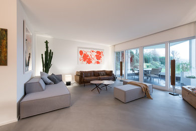 Offenes, Großes Modernes Wohnzimmer ohne Kamin mit weißer Wandfarbe, Betonboden und grauem Boden in Köln