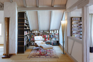 Foto de biblioteca en casa abierta bohemia pequeña sin chimenea y televisor con paredes blancas y suelo de madera clara