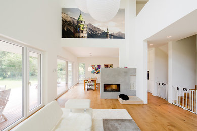 Großes, Offenes Modernes Wohnzimmer mit weißer Wandfarbe, braunem Holzboden, Gaskamin und Kaminumrandung aus Beton in Düsseldorf