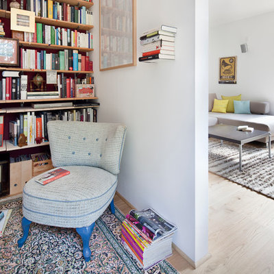 Family room library - mid-sized eclectic open concept light wood floor family room library idea in Berlin with white walls and a tv stand