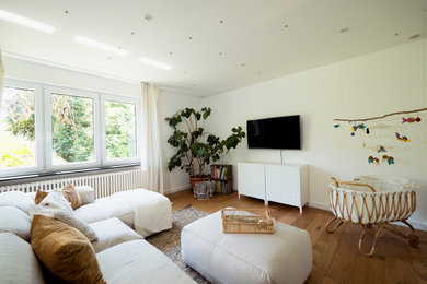 Foto de sala de estar abierta de tamaño medio con paredes blancas, suelo de madera en tonos medios, televisor colgado en la pared y suelo marrón