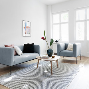 Abgetrenntes Skandinavisches Wohnzimmer mit weißer Wandfarbe, hellem Holzboden und beigem Boden in Berlin
