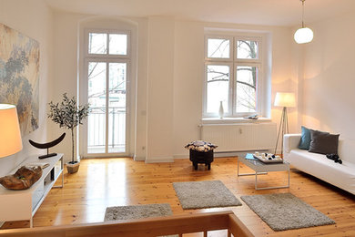 Großes, Fernseherloses, Abgetrenntes Modernes Wohnzimmer ohne Kamin mit weißer Wandfarbe und hellem Holzboden in Berlin