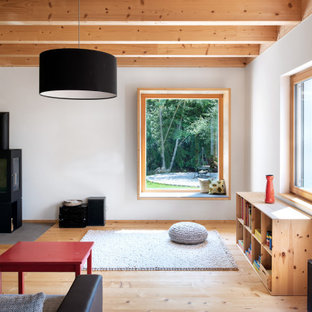 Mittelgroßes, Fernseherloses Landhaus Wohnzimmer mit weißer Wandfarbe, hellem Holzboden, Kaminofen, Kaminumrandung aus Metall und beigem Boden in München