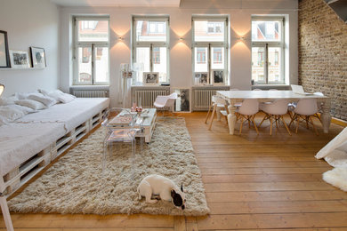 Mittelgroßes, Offenes Industrial Wohnzimmer ohne Kamin mit weißer Wandfarbe und braunem Holzboden in Köln