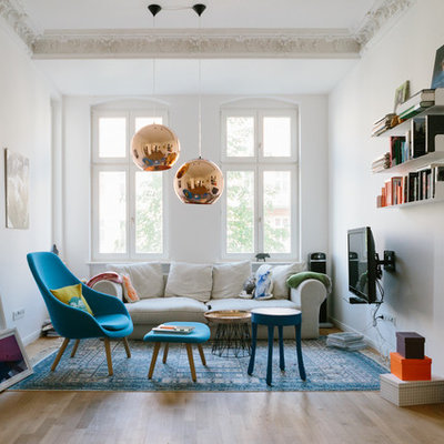 Inspiration for a mid-sized eclectic enclosed light wood floor family room remodel in Berlin with white walls, a wall-mounted tv and no fireplace