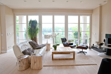 Offenes, Großes, Fernseherloses Modernes Wohnzimmer mit beiger Wandfarbe, hellem Holzboden und Kamin in Berlin
