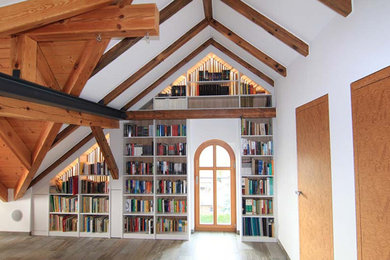 Cette photo montre un salon avec une bibliothèque ou un coin lecture, un mur blanc et parquet peint.