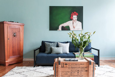 Kleines, Fernseherloses Stilmix Wohnzimmer ohne Kamin mit blauer Wandfarbe, hellem Holzboden und braunem Boden in Berlin