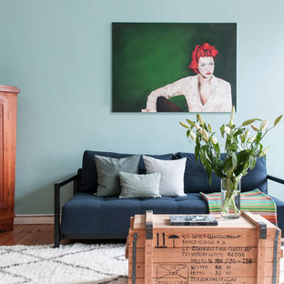 Kleines, Fernseherloses Stilmix Wohnzimmer ohne Kamin mit blauer Wandfarbe, hellem Holzboden und braunem Boden in Berlin