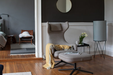 Modernes Wohnzimmer mit schwarzer Wandfarbe, hellem Holzboden und braunem Boden in Berlin