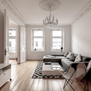 Nordisches Wohnzimmer mit weißer Wandfarbe, braunem Holzboden und braunem Boden in Hamburg