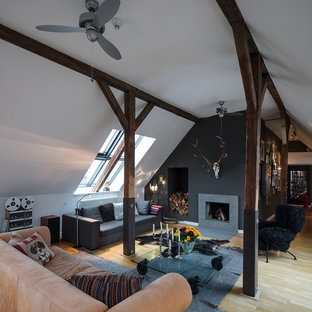 Kleines, Repräsentatives, Fernseherloses, Offenes Uriges Wohnzimmer mit schwarzer Wandfarbe, hellem Holzboden, Kamin, beigem Boden und Kaminumrandung aus Beton in Hamburg