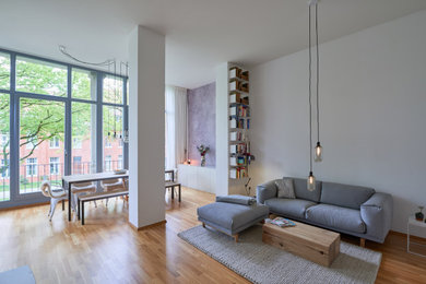 Offenes Modernes Wohnzimmer mit weißer Wandfarbe, braunem Holzboden und braunem Boden in Hamburg