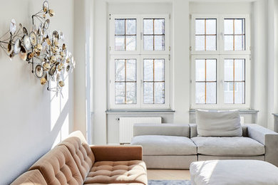 Modernes Wohnzimmer ohne Kamin mit weißer Wandfarbe, hellem Holzboden und beigem Boden in Köln