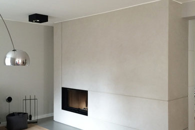 Großes, Repräsentatives, Fernseherloses, Offenes Modernes Wohnzimmer mit weißer Wandfarbe, hellem Holzboden, Kaminofen, Kaminumrandung aus Beton und beigem Boden in Berlin