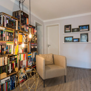 Kleine, Fernseherlose Moderne Bibliothek ohne Kamin mit grauer Wandfarbe und braunem Holzboden in Nürnberg