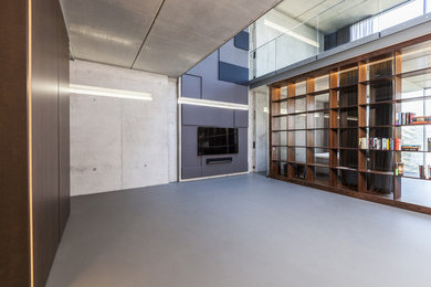 Diseño de salón abierto contemporáneo extra grande con paredes grises, suelo de cemento y pared multimedia