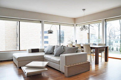 Mittelgroßes Modernes Wohnzimmer ohne Kamin mit weißer Wandfarbe, braunem Holzboden und TV-Wand in Sonstige