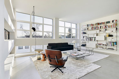 Cette image montre un grand salon design ouvert avec un mur blanc, sol en béton ciré, aucun téléviseur, un sol gris, une bibliothèque ou un coin lecture, aucune cheminée et canapé noir.
