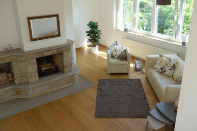 Geräumiges, Offenes Modernes Wohnzimmer mit hellem Holzboden, Kaminofen und Kaminumrandung aus Stein in Bremen