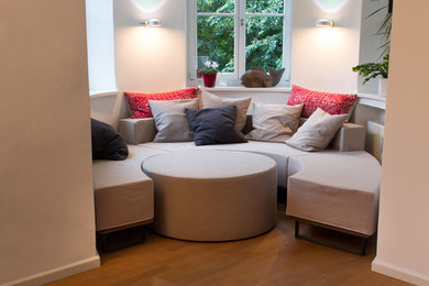 Ejemplo de salón abierto minimalista de tamaño medio con paredes blancas y suelo de madera clara