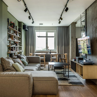 Mittelgroßes, Offenes Modernes Wohnzimmer mit grüner Wandfarbe, braunem Holzboden, Wand-TV und braunem Boden in Berlin