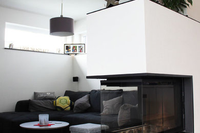 Offenes Nordisches Wohnzimmer mit weißer Wandfarbe, Vinylboden, Eckkamin, verputzter Kaminumrandung und braunem Boden in Stuttgart