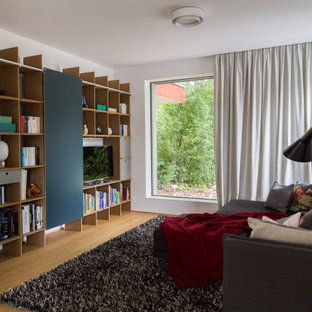 Offenes Modernes Wohnzimmer ohne Kamin mit weißer Wandfarbe, braunem Holzboden, freistehendem TV und braunem Boden in München