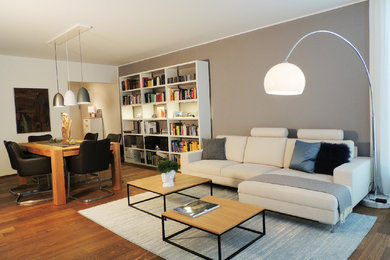 Geräumiges, Offenes Modernes Wohnzimmer mit grauer Wandfarbe und dunklem Holzboden in Sonstige
