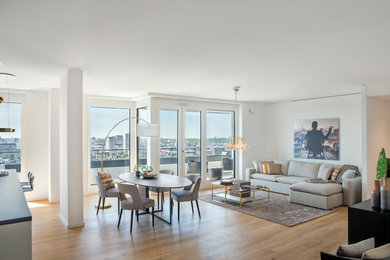 Modelo de sala de estar tipo loft actual grande sin chimenea con paredes blancas, suelo de madera en tonos medios y suelo marrón