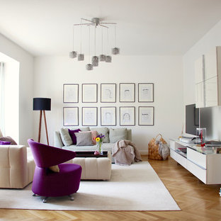 Modernes Wohnzimmer mit weißer Wandfarbe, braunem Holzboden, freistehendem TV und braunem Boden in Frankfurt am Main