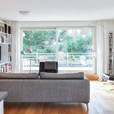 Danish open concept light wood floor family room photo in Munich with white walls, a plaster fireplace, a media wall and a ribbon fireplace
