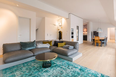 Offenes, Großes Modernes Wohnzimmer ohne Kamin mit weißer Wandfarbe, hellem Holzboden, Eck-TV und beigem Boden in München
