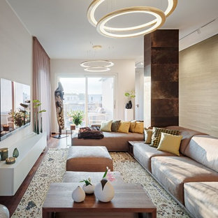 Offenes, Großes Modernes Wohnzimmer mit dunklem Holzboden, Tunnelkamin, Kaminumrandung aus Stein, Wand-TV, beiger Wandfarbe und braunem Boden in Berlin