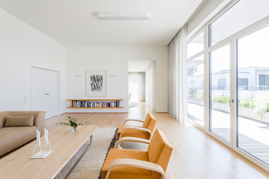 Cette photo montre une grande salle de séjour moderne ouverte avec un mur blanc, parquet clair et un téléviseur dissimulé.