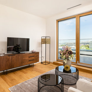 Repräsentatives, Abgetrenntes, Kleines Modernes Wohnzimmer ohne Kamin mit weißer Wandfarbe, braunem Holzboden, freistehendem TV und beigem Boden in München