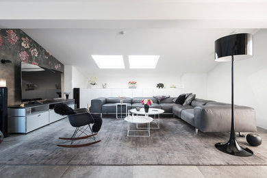 Medium sized contemporary formal open plan living room feature wall in Nuremberg with white walls, a freestanding tv, grey floors and no fireplace.