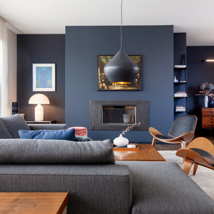 Großes, Repräsentatives, Fernseherloses, Offenes Modernes Wohnzimmer mit blauer Wandfarbe, Kamin, Kaminumrandung aus Metall und braunem Boden in Berlin