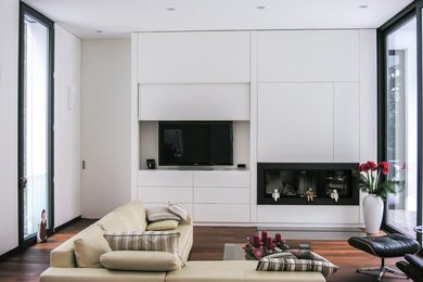 Modernes Wohnzimmer mit weißer Wandfarbe, braunem Holzboden, Gaskamin, verstecktem TV und braunem Boden in Frankfurt am Main