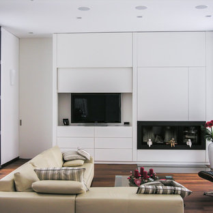 Modernes Wohnzimmer mit weißer Wandfarbe, braunem Holzboden, Gaskamin, verstecktem TV und braunem Boden in Frankfurt am Main