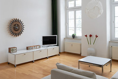 Klassisk inredning av ett mellanstort allrum med öppen planlösning, med vita väggar, mellanmörkt trägolv och en fristående TV