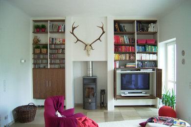 Ejemplo de sala de estar con biblioteca actual grande con paredes blancas, todas las chimeneas, televisor retractable y suelo beige