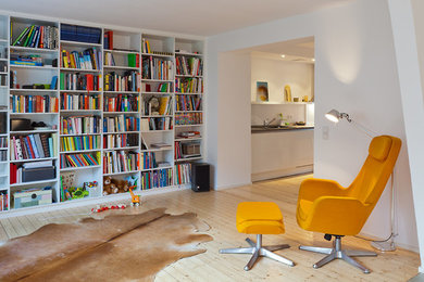 Diseño de biblioteca en casa abierta actual grande con paredes blancas y suelo de madera clara