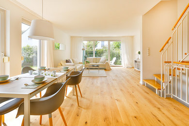 Mittelgroßes, Offenes, Fernseherloses Nordisches Wohnzimmer ohne Kamin mit weißer Wandfarbe, gebeiztem Holzboden und braunem Boden in Essen