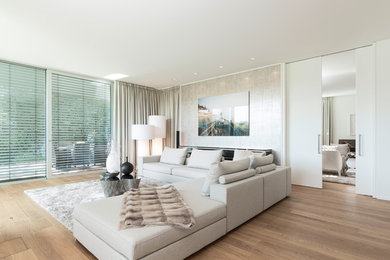 Imagen de sala de estar cerrada contemporánea grande sin televisor y chimenea con paredes blancas, suelo de madera en tonos medios y suelo marrón