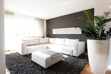 Mittelgroßes, Offenes Modernes Wohnzimmer mit weißer Wandfarbe, gebeiztem Holzboden und TV-Wand in Stuttgart